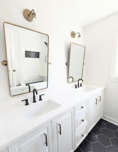 A black and white bathroom with two sinks and a mirror.